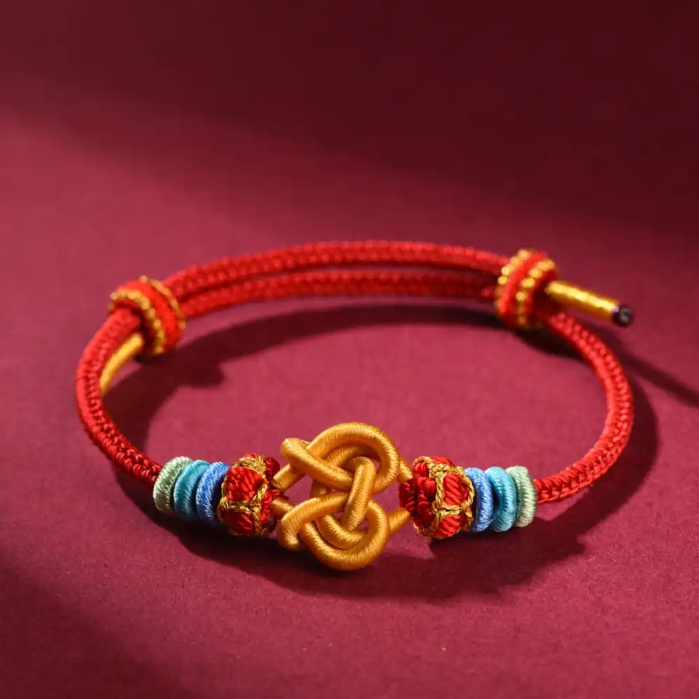Handwoven red cord bracelet with golden knot and colorful blessing threads