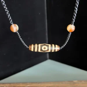 Three-eye Tibetan Dzi bead choker necklace with treated patina and natural Alxa agate accents on hand-braided adjustable black cord