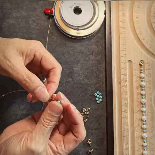 Duo's Design handmade jewelry process with Kris Nature thread spool, turquoise beads, pearl strand, and beading tools