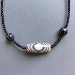 Hero shot of Buddha eye silk agate necklace with symmetrical black agate accents on gray | Glint & Grain