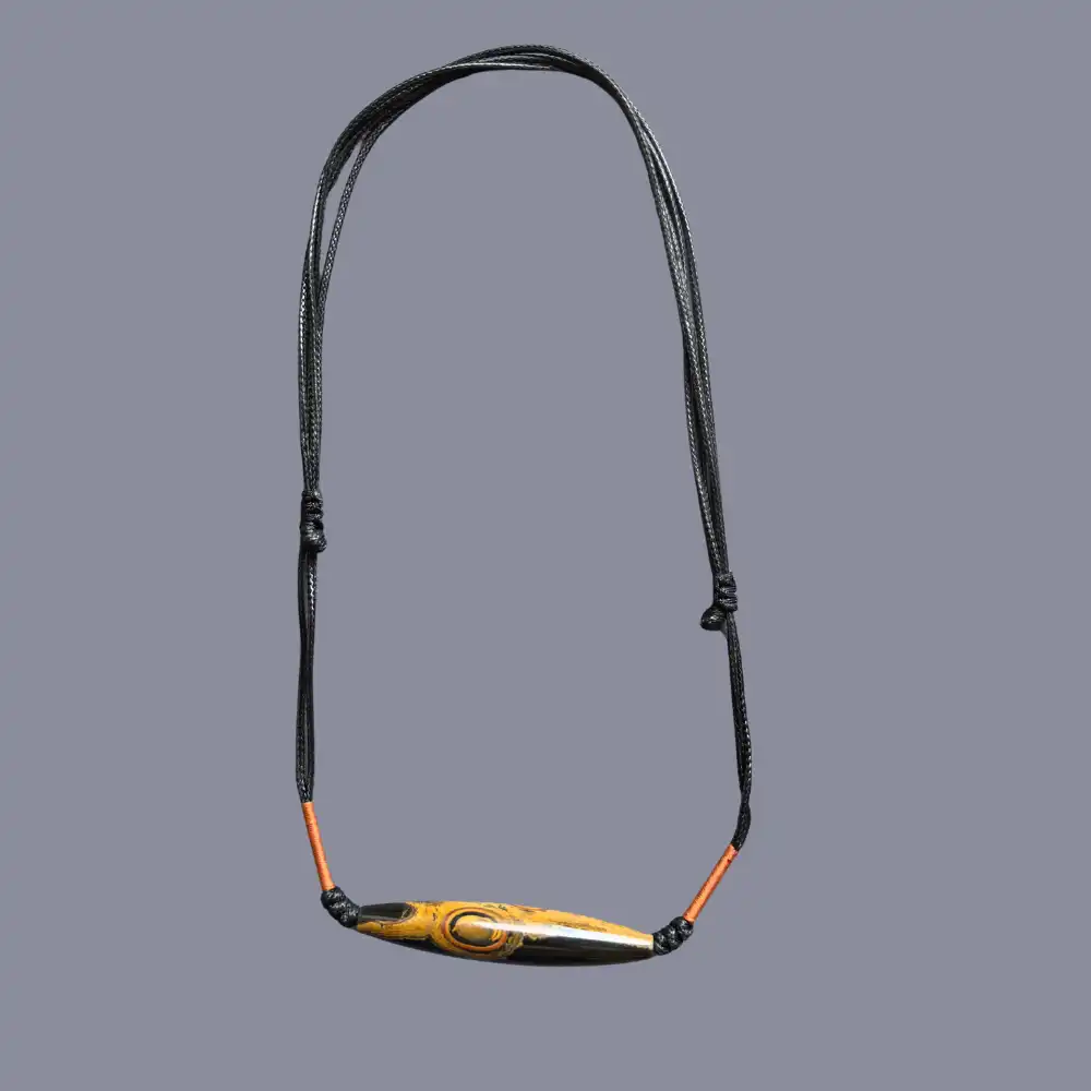 Front and back view of the two-eye eye-stone lance pendant showing pattern and glossy black side | Glint & Grain