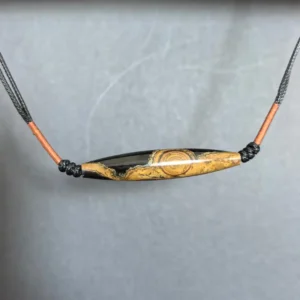 Top view of the lance-shaped two-eye eye-stone pendant showing layered ochre, rust-red and black banding | Glint & Grain |
