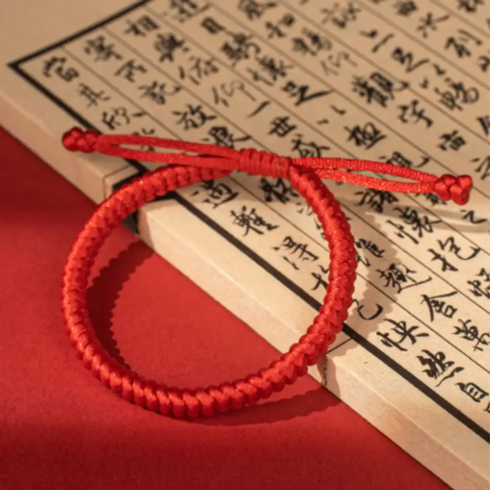 Lucky red string bracelet resting on traditional Chinese sutra book, blessing gift