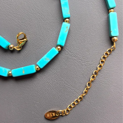 Close-up of the magnesite turquoise necklace's copper-gold plated clasp and extender chain on a charcoal background.