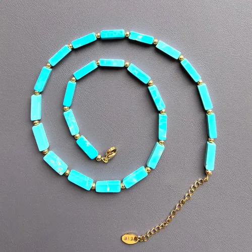 Magnesite turquoise necklace with gold-tone spacer beads, arranged in a spiral flat-lay with the clasp and extender chain visible.